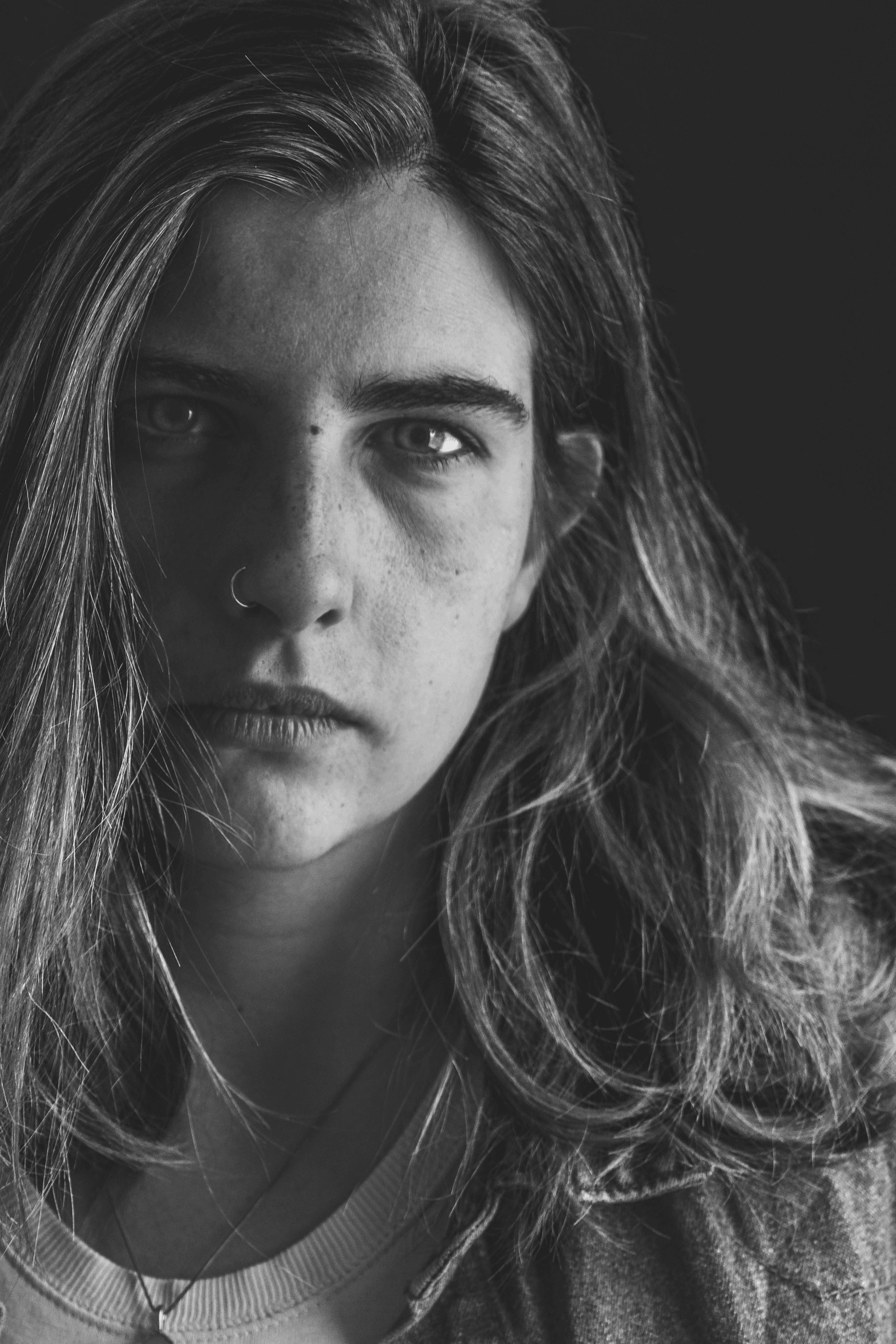 Portrait noir et blanc en gros plan d'une jeune femme au piercing narine, regard intense