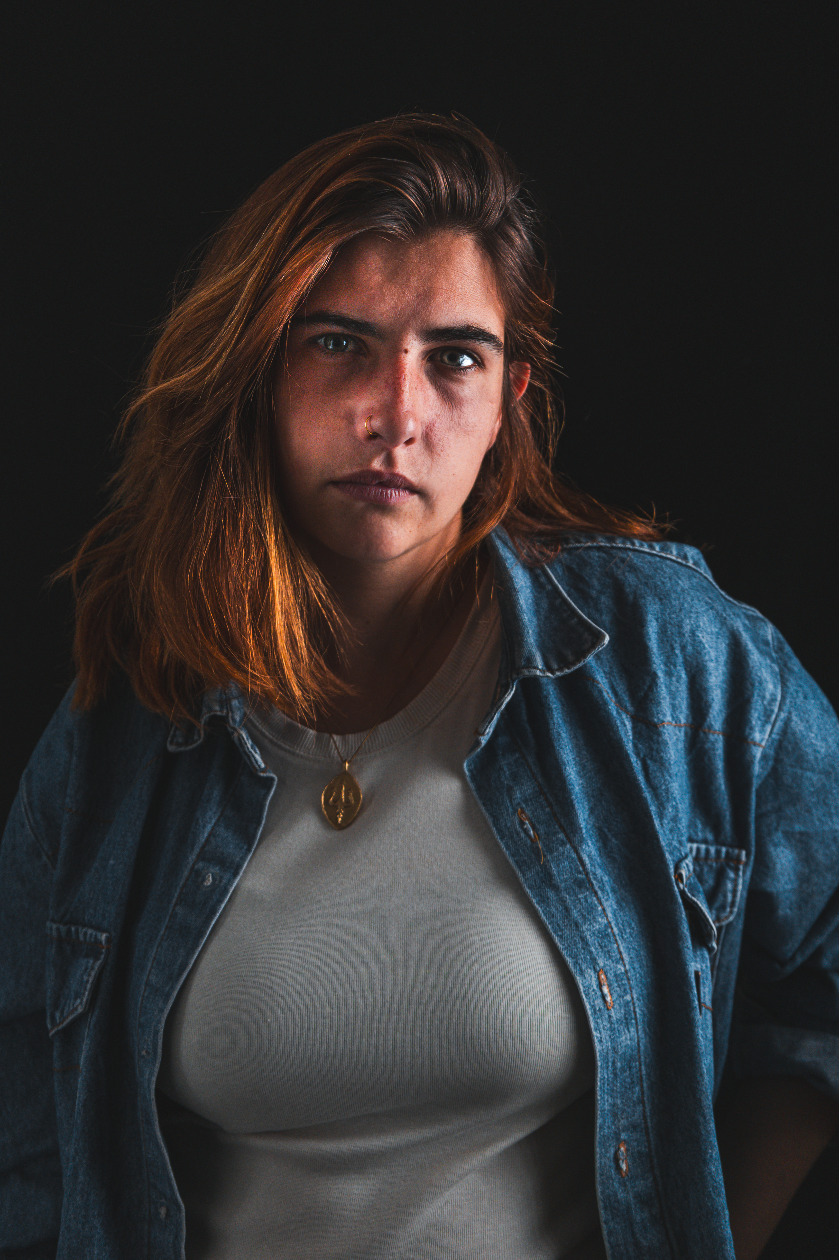 Portrait noir et blanc d'une femme en veste en jean portant un pendentif doré
