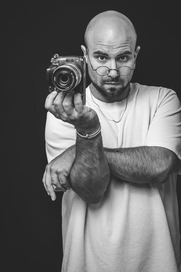 Autoportrait de Damien Benvenuti tenant un appareil photo vintage face à l'objectif