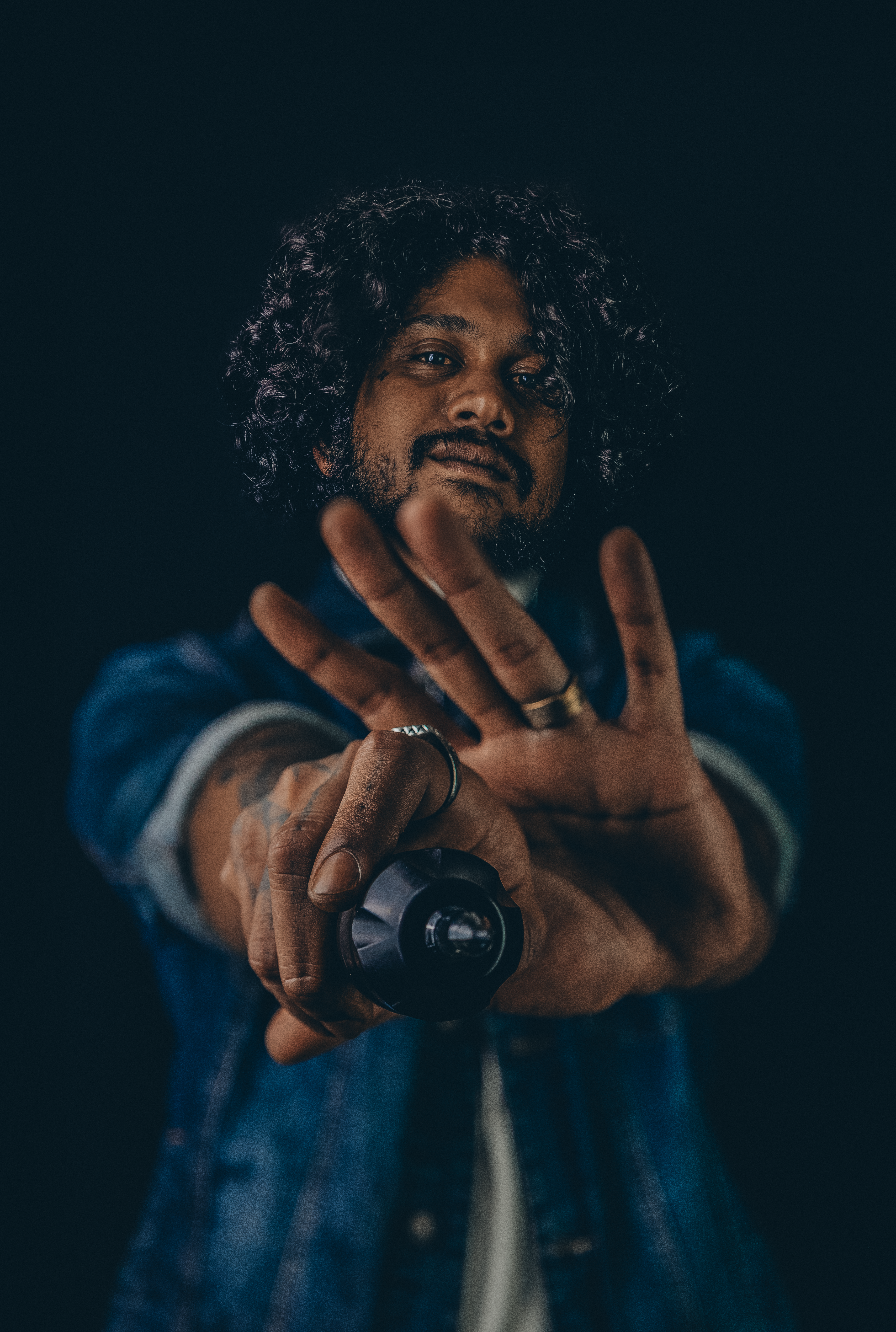 Portrait d'un homme aux cheveux bouclés tendant un objectif photo vers l'objectif