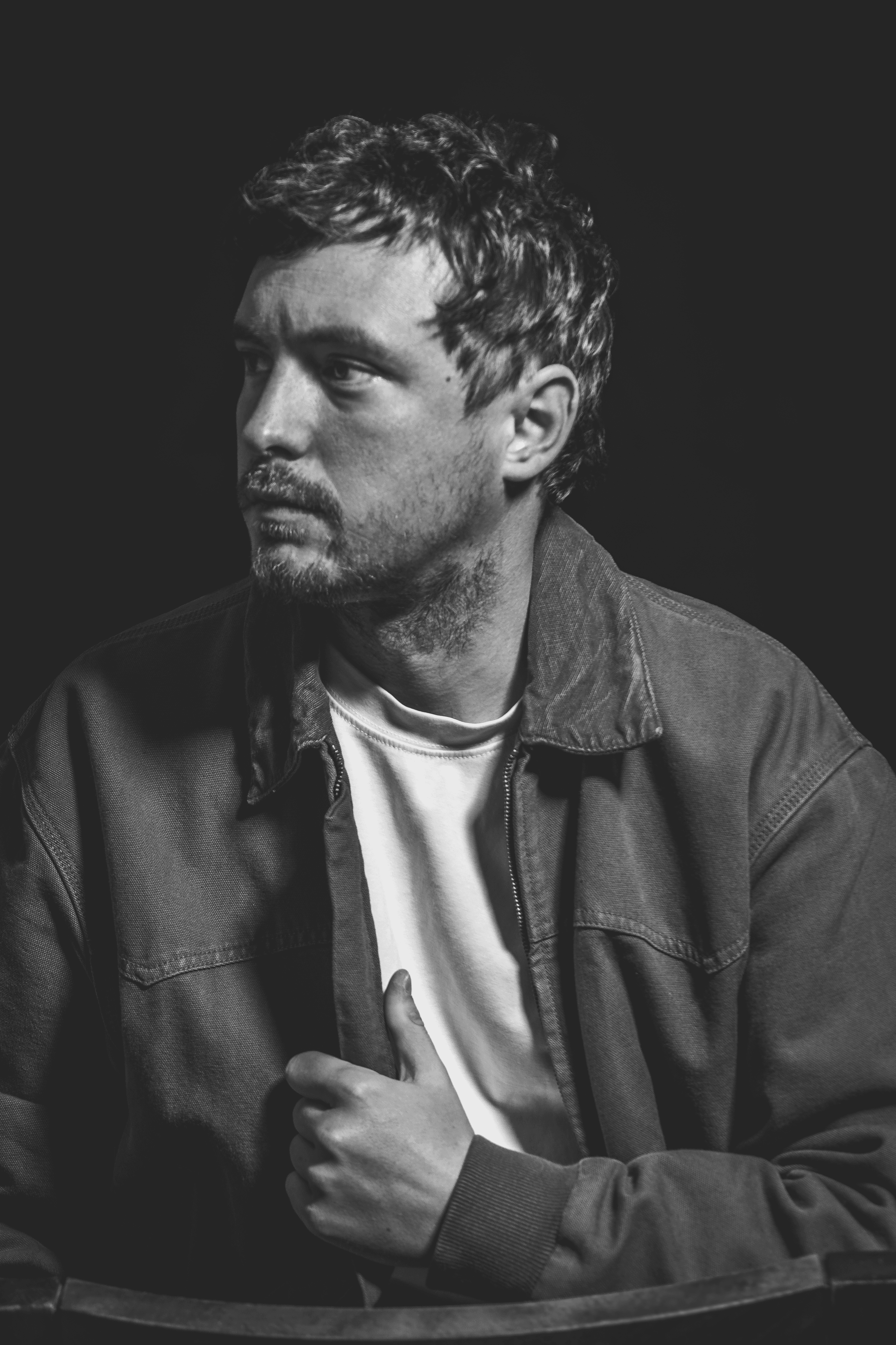 Portrait noir et blanc d'un homme en veste regardant hors champ, expression pensive