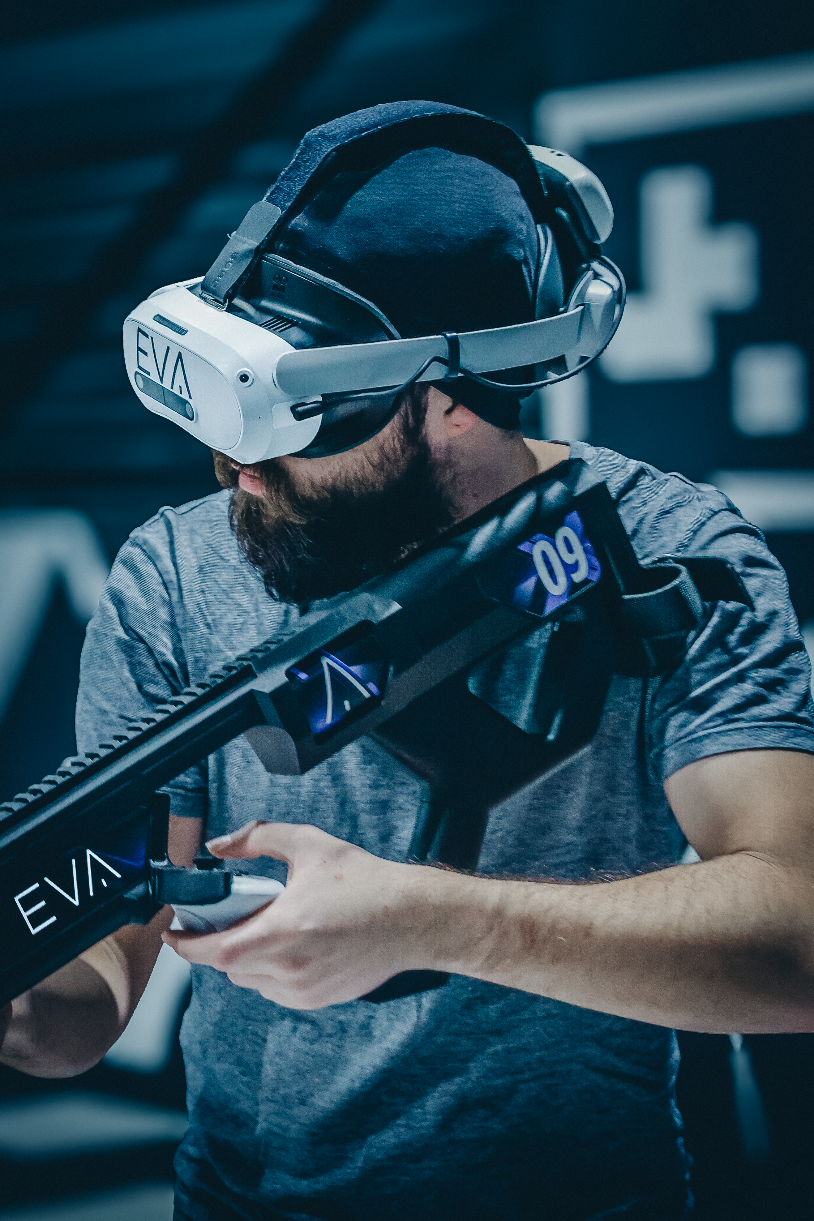 Joueur équipé d'un casque de réalité virtuelle et d'une arme lumineuse, geste tendu vers l'objectif