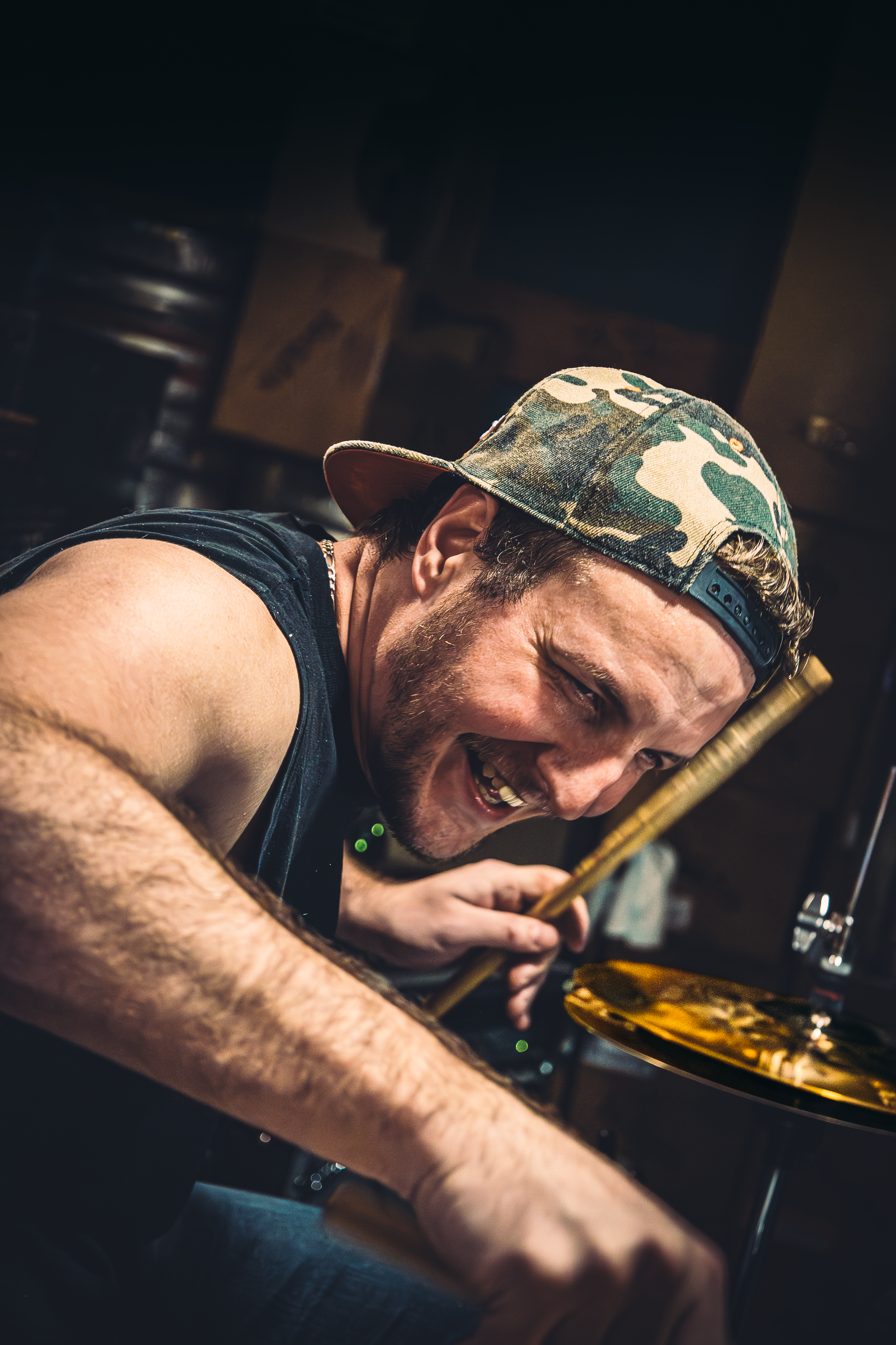 Batteur riant en gros plan, baguettes en main, reportage live rapproché