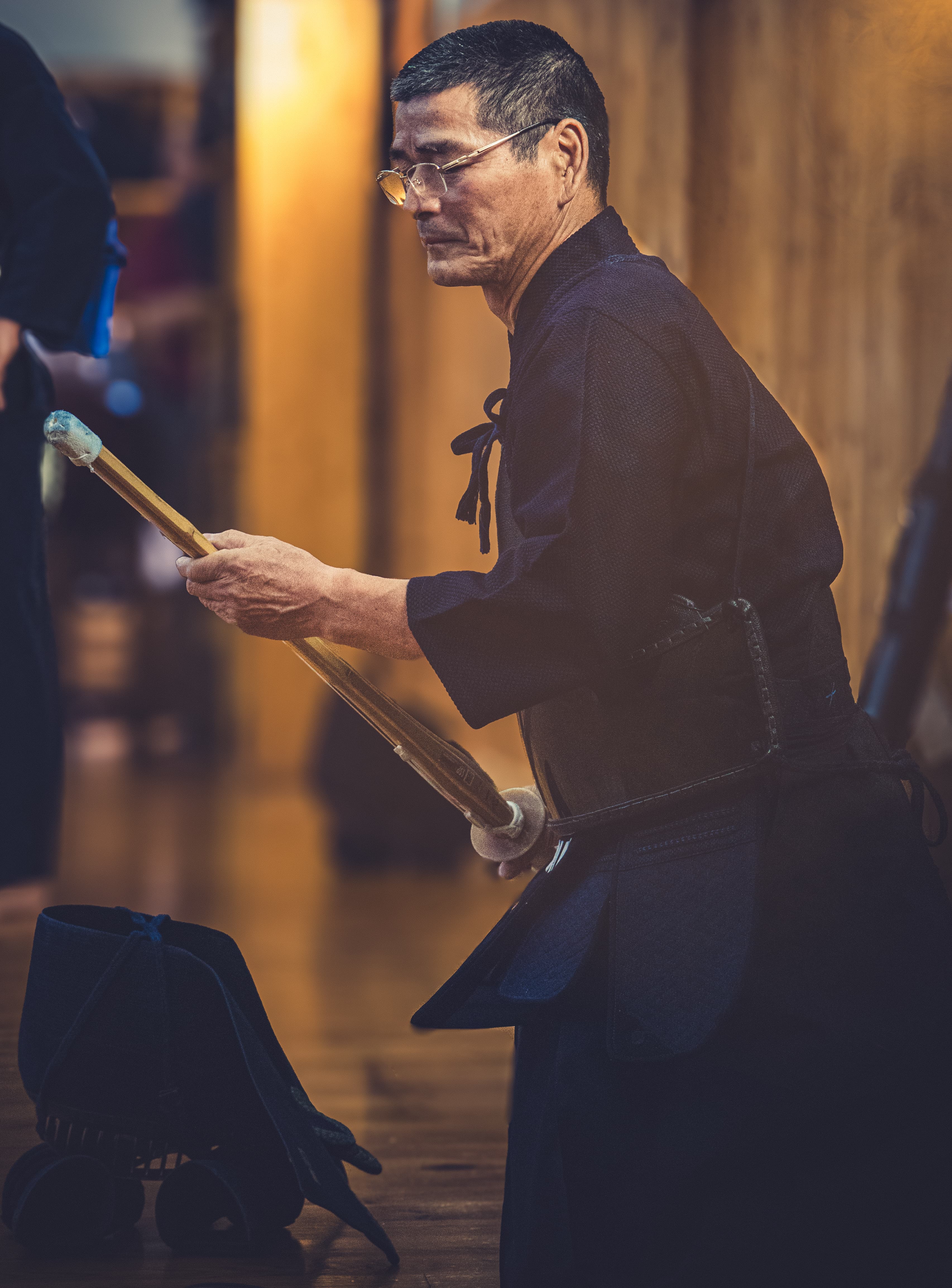 Pratiquant de kendo ajustant son shinai avant l'entraînement, lumière chaude en dojo